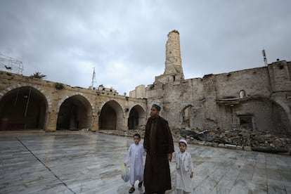 Un hombre con dos niños se dirigen a la oración en la Gran Mezquita de Gaza, que resultó gravemente dañada por los ataques israelíes. 