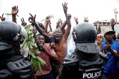 Um grupo de pessoas celebra os resultados na frente da polícia, em Kinshasa. O anúncio encerra dois anos de atrasos e incertezas, já que o presidente Joseph Kabila - no poder há quase 18 anos - por lei concluiu seu segundo e último mandato, ancorando-se no poder desde dezembro de 2016.