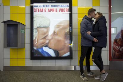 Una pareja se besa junto a un cartel que representa al político holandés Geert Wilders y al presidente ruso, Vladimir Putin, en el metro de Ámsterdam (Holanda), el 3 de abril de 2016.