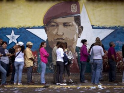 Fila em Caracas diante de um muro pintado com o rosto de Hugo Chávez.