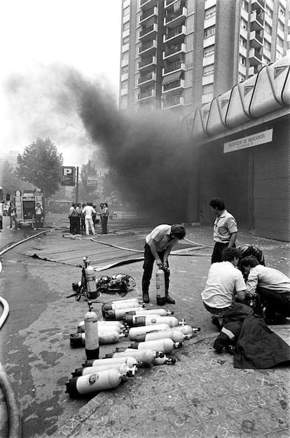 Miembros de los servicios de emergencias preparan bombonas de oxígeno para entrar en los grandes almacenes de Hipercor en Barcelona, tras el atentado de ETA el 19 de junio de 1987. 