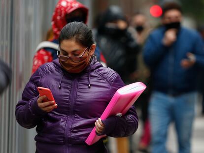 Una mujer consulta su teléfono móvil mientras anda por Santiago de Chile.