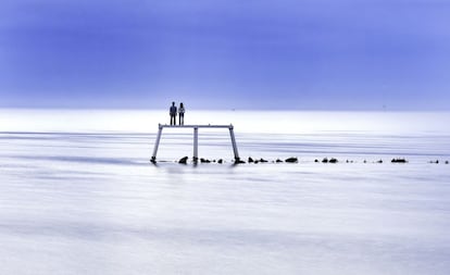 Vista de la obra de Sean Henery, 'The Couple', instalada en Newbiggin-by-the-Sea, una ciudad costera de Inglaterra. El Mar del Norte presenta un aspecto calmado debido a las altas temperaturas que vive Reino Unido, inusuales en esta época del año.