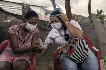 Mayerlin Vergara Pérez, de 44 años, habla con una líder comunitaria en una visita en Villa Del Sur, un barrio informal de Riohacha (La Guajira) en el que viven 3.000 migrantes.