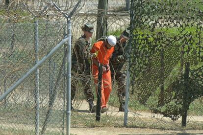 Un detenido es trasladado por dos soldados en la prisión de Guantánamo en febrero de 2002.