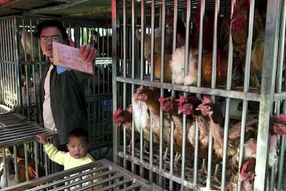 Un vendedor de pollos en un mercado de Pekín intenta evitar que su puesto sea fotografiado.