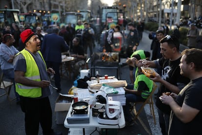 Algunos de los agricultores de la protesta de Barcelona preparan comida en el paseo de Gracia, este miércoles. 
