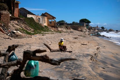 Un niño sentado en un tronco contempla la playa de Atafona.