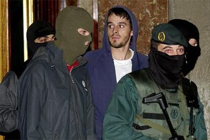 Asier Arriola (con capucha azul) sale rodeado de miembros de la Guardia Civil durante el registro anoche en un piso del barrio bilbaino de Zorroza.