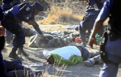 Unos policías inspeccionan los cuerpos sin vida de unos mineros tras los tiroteos acontecidos cerca de una planta minera en Rustenburgo (Sudáfrica) hoy.