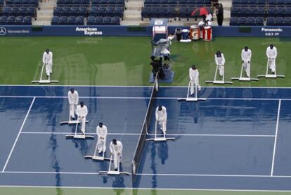 Los operarios del torneo intentan secar la pista antes de la confirmación oficial del aplazamiento de la final entre Nadal y Djokovic