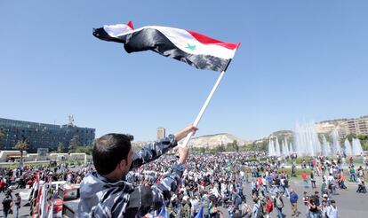 Un hombre ondea una bandera nacional durante una manifestación en apoyo al Gobierno sirio y su presidente, Bachar al Asad, en Damasco (Siria).