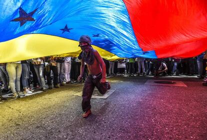 Un niño corre debajo de una bandera de Venezuela durante una protesta en Caracas contra los ataques a los periodistas y medios gráficos.