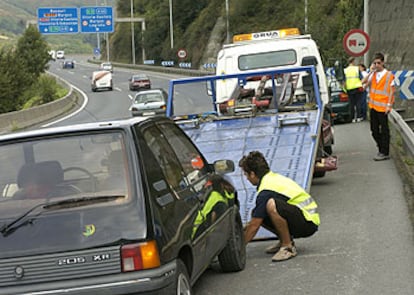 Un gruista retira un vehículo averiado en la A-8, cerca de Bilbao, tras la desconvocatoria del paro de grúas.