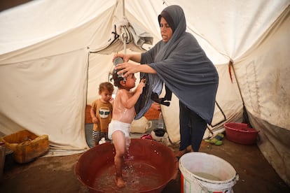 Una mujer palestina lava a su hijo en una tienda de campaña en Deir al Balah, en la franja de Gaza, el pasado 8 de julio.