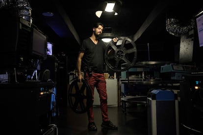 El proyeccionista francés Benjamin Louis posa para una fotografía con bobinas de películas en la sala de proyección del cine Louxor de París, el 19 de abril de 2018.