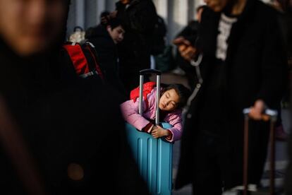 Una niña descansa agarrada a su maleta mientras aguarda a las puertas de la estación de tren de Pekín (China), el 1 de febrero de 2018. 