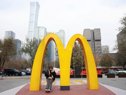 A woman sits on a swing attached to a giant sign of McDonald's, outside its themed exhibition in Beijing, China December 4, 2023