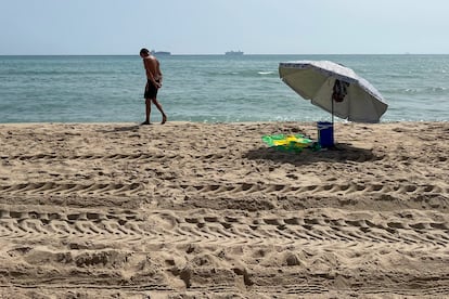 Una persona pasea por una de las tres playas del sur de València afectadas desde el martes por un vertido de hidrocarburos que han reabierto este jueves el acceso al público, pero lo han hecho con bandera roja, que prohíbe el baño.