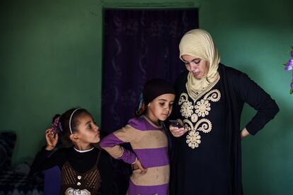 Fátima mira el teléfono móvil junto a dos de sus hijas.