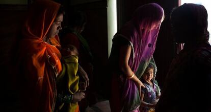 Varias mujeres salen con sus niños del recinto donde acaban de asistir a una charla de la ONG local Mamta.
