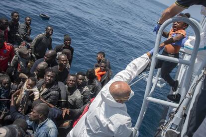 Un marinero italiano iza a uno de los seis niños que viajaban a bordo de la patera este jueves en el Estrecho.