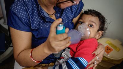 Un niño con problemas respiratorios es atendido con un inhalador en la India.