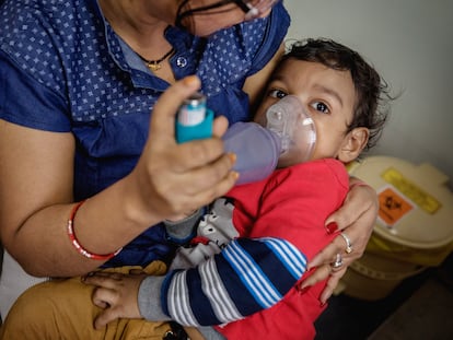 Un niño con problemas respiratorios es atendido con un inhalador en la India.