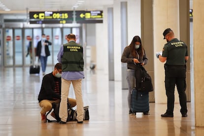 Una pareja de la Guardia Civil realiza un control a unos viajeros en El Prat durante en mayo de 2020, durante la pandemia de coronavirus.