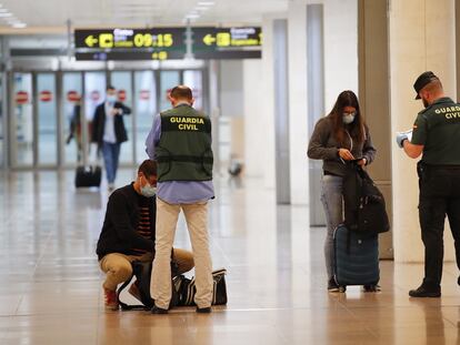 Una pareja de la Guardia Civil realiza un control a unos viajeros en El Prat durante en mayo de 2020, durante la pandemia de coronavirus.