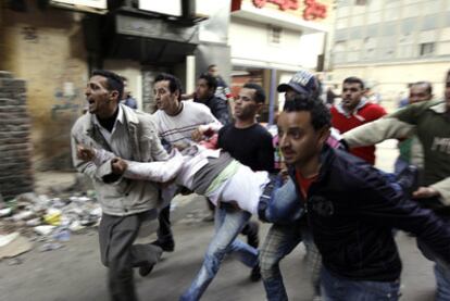 Varios jóvenes transportan a un herido en enfrentamientos con la policía antidisturbios en El Cairo.