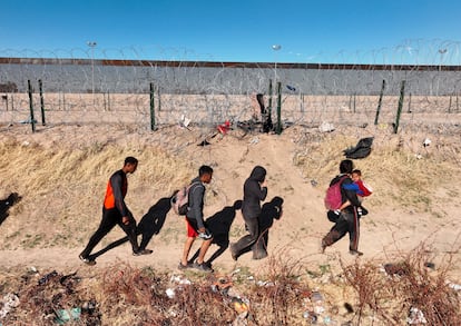 Un grupo de migrantes camina junto al muro en Río Grande, Texas.