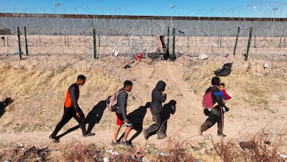 A group of migrants walk by the wall in Rio Grande, Texas.