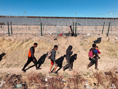 Un grupo de migrantes camina junto al muro en Río Grande, Texas.