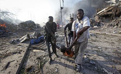 Un grupo de personas trasladan el cuerpo de un hombre asesinado en una explosión de un camión bomba en Mogadiscio (Somalia), el 14 de octubre de 2017.