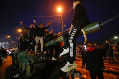 Los vecinos de Damasco, encaramados a un carro de combate, celebran la llegada de los rebeldes a la capital en las primeras horas de este domingo. 