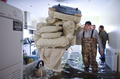 Egham ha sido una de las localidades británicas que ha sufrido las inundaciones provocadas por el desbordamiento del río Támesis debido al temporal de lluvia. En la imagen unos residentes de la localidad entran en su casa para intentar recuperar sus pertenencias.