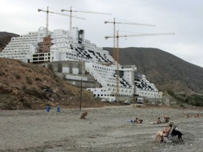 Ba&ntilde;istas en la playa de El Algarrobico, al fondo el hotel, en Carboneras.