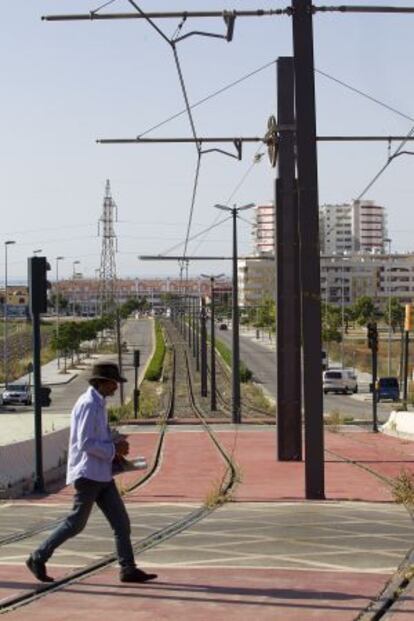 Un paseante atraviesa las vías del tranvía.