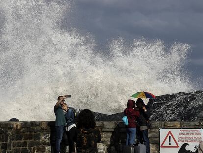 Varias personas toman fotografas y observan las grandes olas que rompen en el espign de la Zurriola de San Sebastin, donde hoy se ha decretado la alerta amarilla por fenmenos costeros.