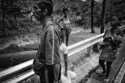 Una familia recoge agua de un cauce cercano a la autopista Francisco Fajardo, en Caracas.