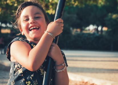 Una niña sonríe mientras se columpia en un parque.