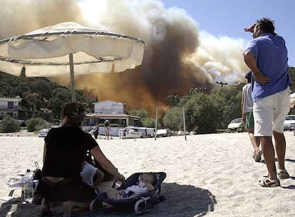 Una familia observa el fuego desde una playa en la isla de Eubea, donde se ha refugiado.