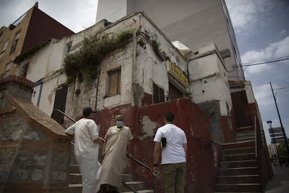Tres hombres conversan frente a un edificio abandonado en el centro de Ceuta, el viernes. 