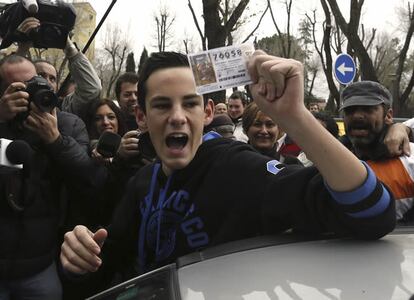 Un joven muestra un décimo del número 76.058 que ha sido agraciado con el primer premio de la Lotería de Navidad, vendido en la administración número 12 de Alcalá de Henares