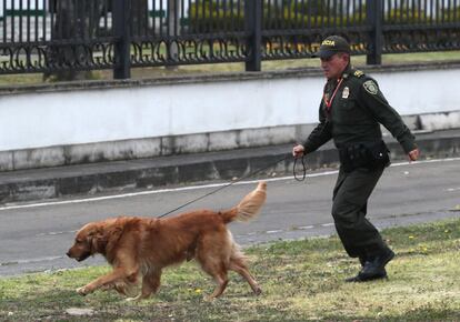 Un agente policial inspecciona con un perro policía los alrededores del lugar en el que se ha producido la explosión del coche bomba, en Bogotá.