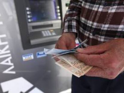 Un hombre saca dinero de un cajero automático. EFE/Archivo