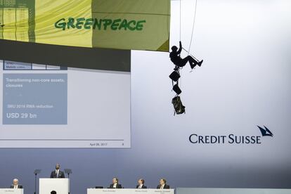 Un activista de Greenpeace se descuelga del techo para desplegar un cartel gigante en protesta contra la construcción del oleoducto Dakota Access (DAPL, por sus siglas en inglés) ante la sorpresa de los directivos del banco de inversiones suizo Credit Suisse durante una junta general de accionistas celebrada en el Hallenstadion de Zúrich (Suiza).