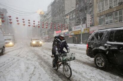 Un ciclista circula entre la nieve en el barrio de Chinatown en Nueva York, 13 de febrero 2014. Según las predicciones, también se espera que las fuertes rachas de viento, que podrían alcanzar los 80 kilómetros por hora, causen pequeñas inundaciones en las costas de Delaware y Maine debido a los golpes de mar.