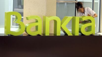 Una operaria limpia un logo de Bankia en Valencia.